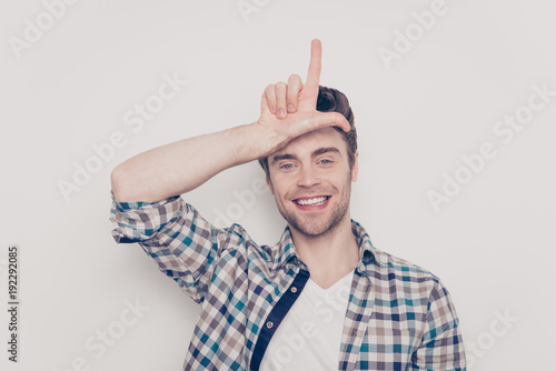 Close up portrait of careless handsome excited cheerful glad funky funny positive laughing joyful with bristle stubble guy making demonstrating loser sign isolated on gray background photo