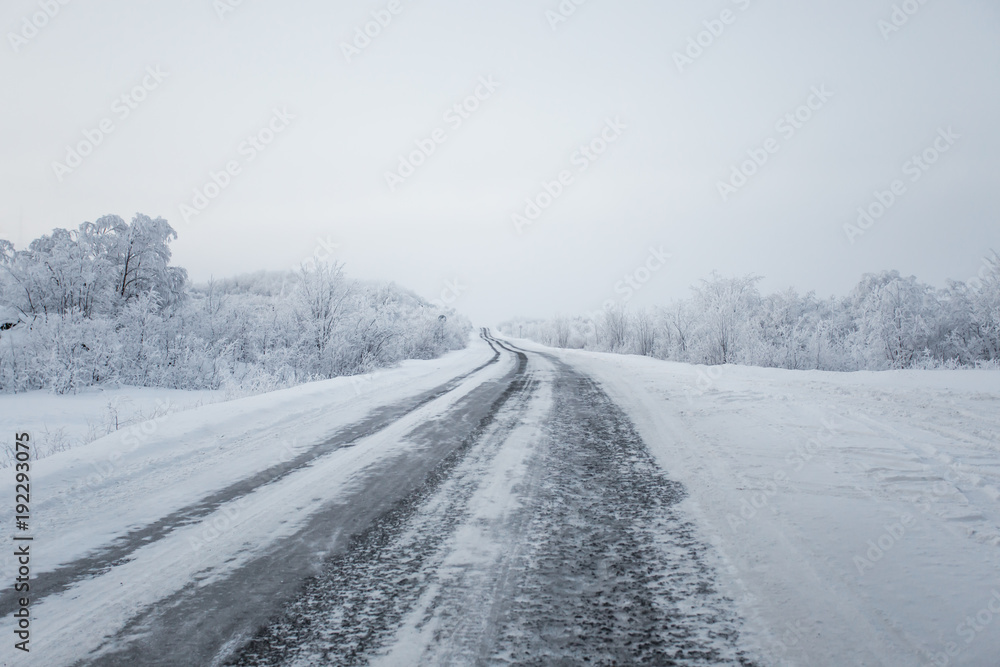 scenic view of empty road with snow covered landscape on cloudy winter day