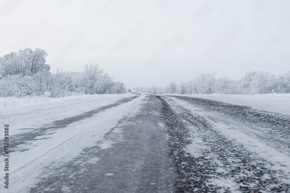 scenic view of empty road with snow covered landscape on cloudy winter day