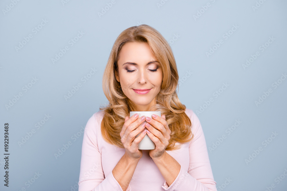 Close up portrait of satisfied pretty peaceful delightful calm woman is smelling aromatic cacao isolated on gray background