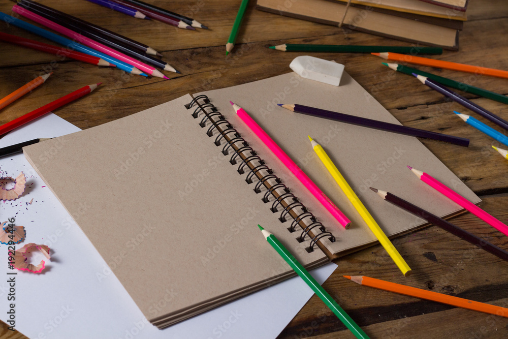 Open Notebook, Blank Paper Sheet, Colored Pencils on the Old Wooden Table Open Notebook, Blank Paper Sheet, Colored Pencils on the Old Wooden Table