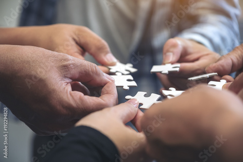 Closeup image of many people hands holding a jigsaw puzzle in circle together