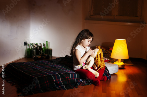 Lonely caucasian girlie in the empty room holding a doll