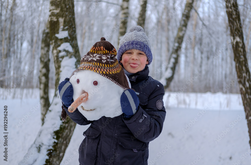 European boy and the snowman in a snowy forest European boy and the snowman in a snowy forest