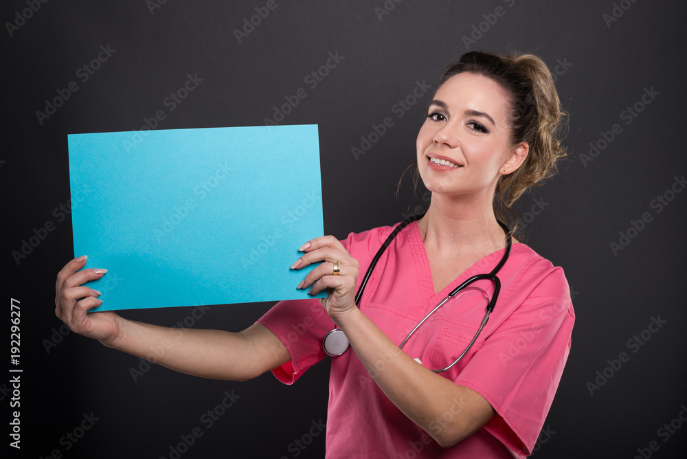 Portrait of beautiful young doctor holding blue cardboard Portrait of beautiful young doctor holding blue cardboard