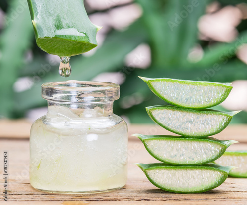 Fresh aloe leaves and aloe gel in the cosmetic jar on wooden table.