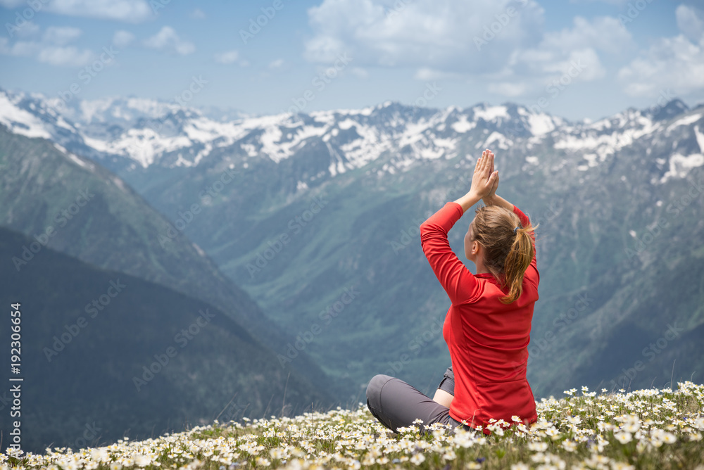 young woman practicing yoga on a mountain top