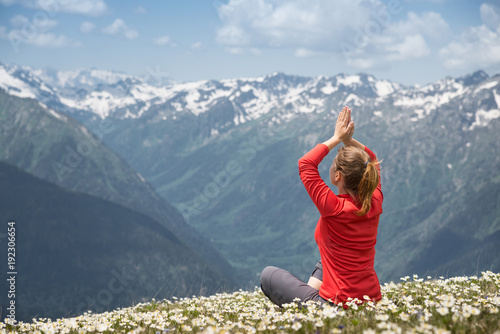 young woman practicing yoga on a mountain top