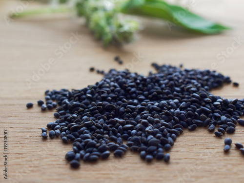 Dried sweet basil or sabja seeds with flower and leaves on wooden background