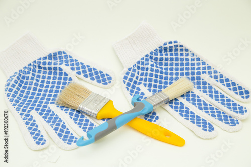 Painting the house. Wooden and plastic paint brushes and protective gloves on white background with copy space, top view, flat lay photo