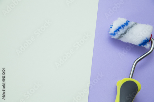 Painting the house. Paint roller on blue and white background with copy space, top view, flat lay photo