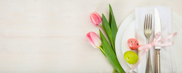 Easter table setting with pink tulips on white wooden background. Top view, copy space, banner