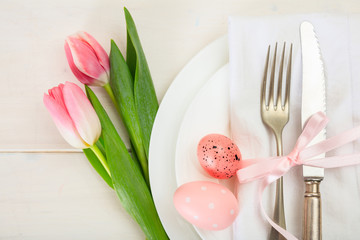 Easter table setting with pink tulips on white wooden background. Top view