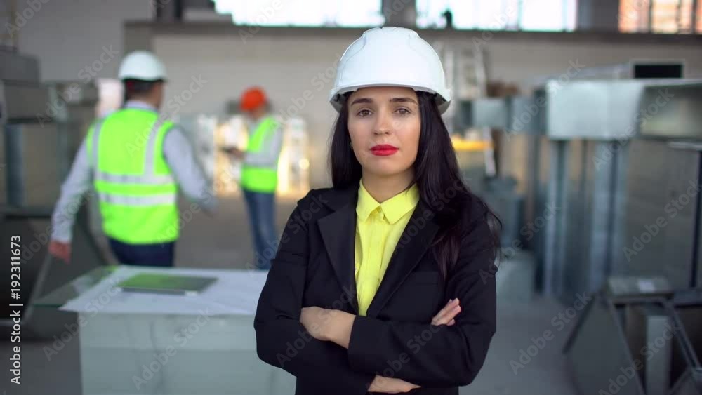 Female engineer standing and male engineer using digital tablet in background. Portrait of female engineer. 4 k airduct of an HVAC system. Air ducts for conditioning and ventilation & fire Female engineer standing and male engineer using digital tablet in background. Portrait of female engineer. 4 k airduct of an HVAC system. Air ducts for conditioning and ventilation & fire