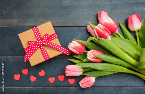 Women's day. Pink tulips and a gift on blue background, top view