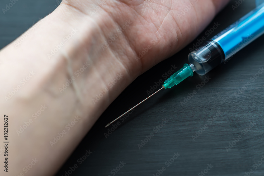 clsoseup of syringe and wooman hand on wooden background clsoseup of syringe and wooman hand on wooden background