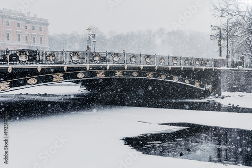 Fontanka river embankment in Saint Petersburg, Russia during snowfall in winter weather. Frozen river Fontanka. Panteleimone bridge and Saint Michael`s Castle.