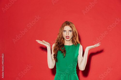Confused ginger woman in green dress shrugs her shoulders © Drobot Dean