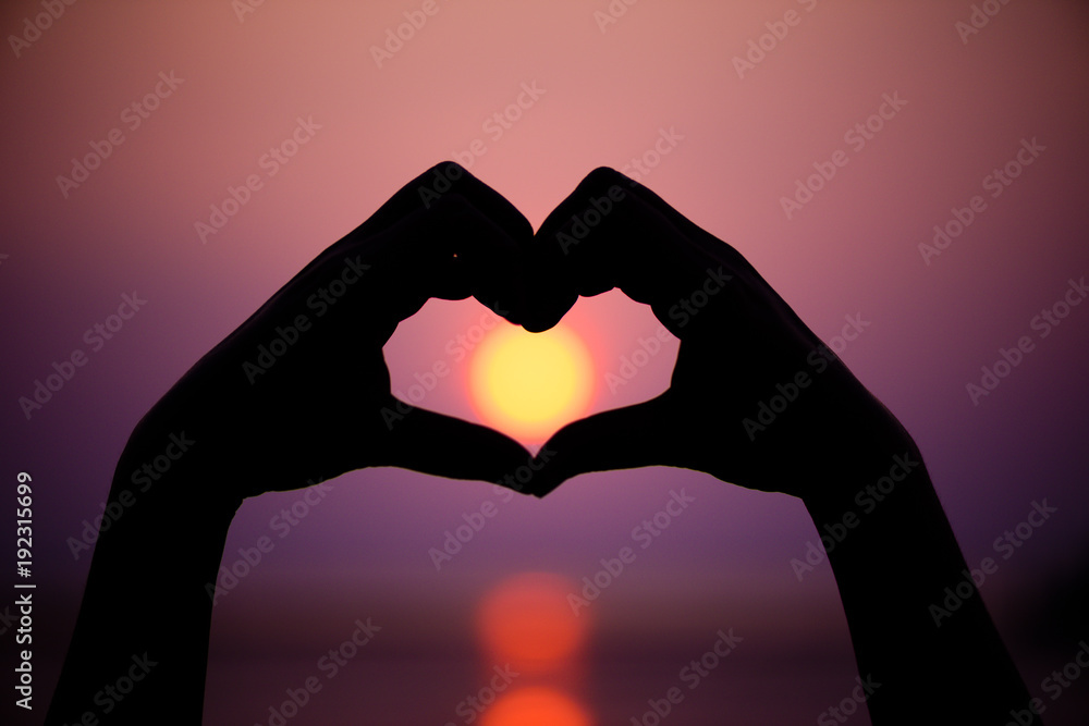 Fototapeta premium Silhouette the woman hands to be heart shape on sunset background. Happy, Love, Valentine's day idea, sign, symbol, concept.