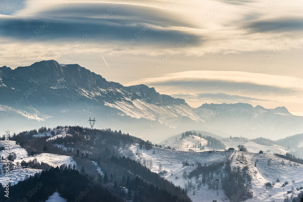 Beautiful winter landscape in the mountains with lenticular clouds and snow,Pestera, Bucegi, Romania
