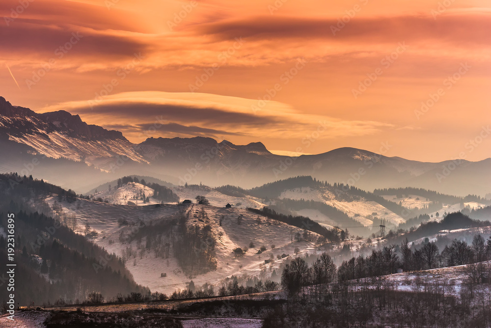 Beautiful winter landscape in the mountains with lenticular clouds and snow in the sunset light, Pestera, Bucegi, Romania