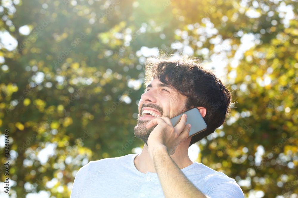 Close up happy young man talking on cellphone outdoors Close up happy young man talking on cellphone outdoors