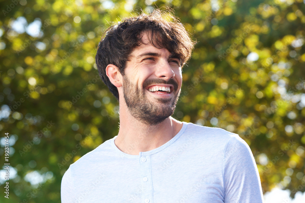 Close up handsome young man with beard smiling outdoors Close up handsome young man with beard smiling outdoors
