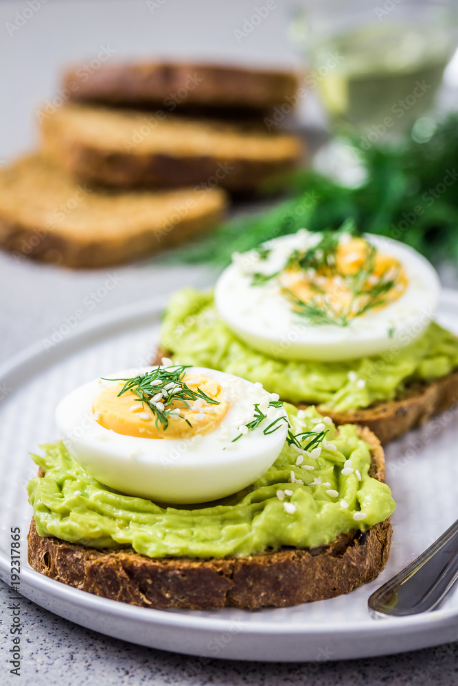 Avocado egg spring toasts on concrete background. Selective focus, close up, space for text.