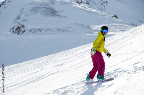 Photo of female athlete wearing helmet and mask, snowboarding from mountain slope