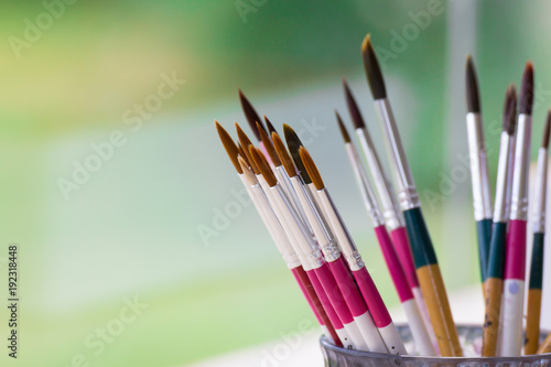 paint brushes in the glass with green natural background