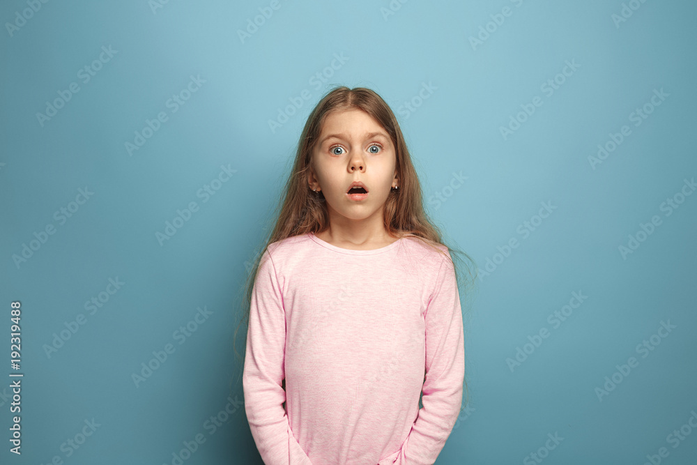 Fototapeta premium The surprise. Teen girl on a blue background. Facial expressions and people emotions concept