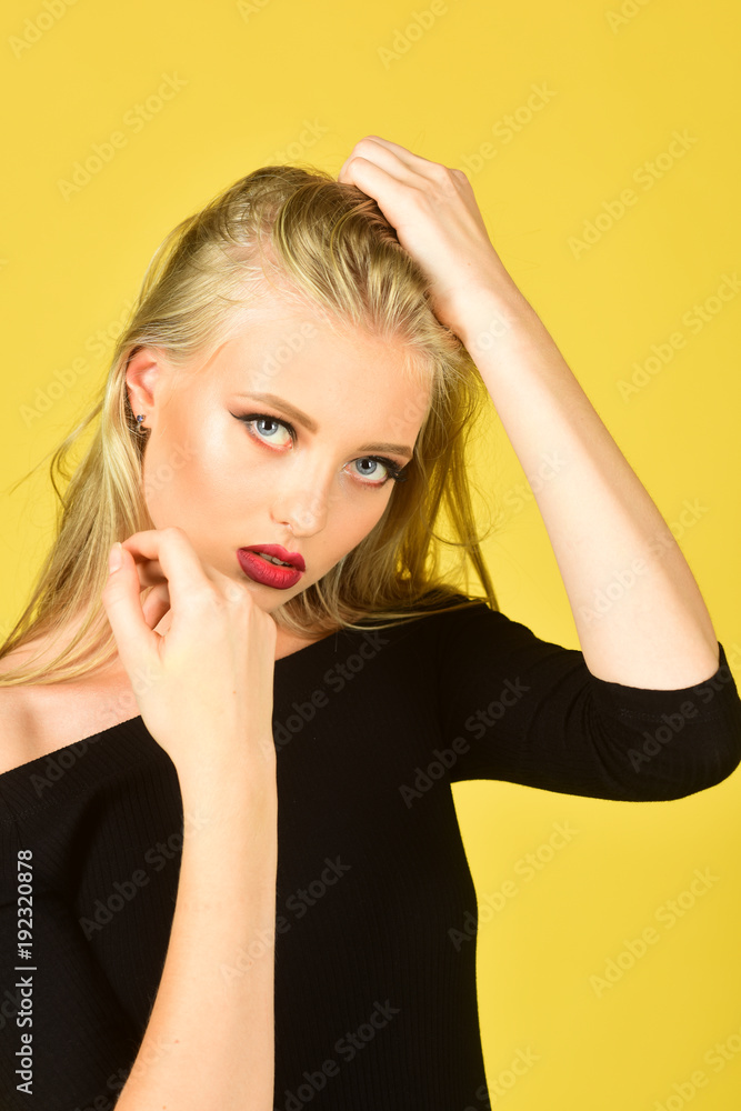 Care and hair products - cosmetics concept. Blonde model girl with red lips, perfect clean skin, straight long hair in elegant black dress.