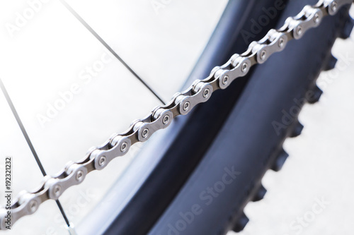 Bicycle wheel and gear detail with a new clean chain, spokes and black mountain bike tire for wallpaper or background