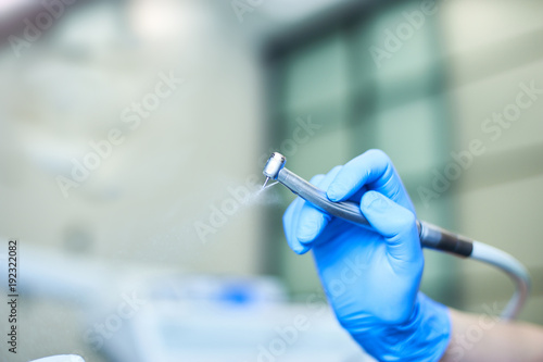 Dentist's hands with blue gloves working with dental drill in dental office. photo