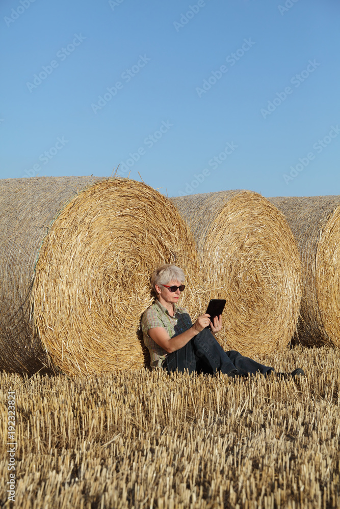 Farmer examining wheat field after harvest using tablet Farmer examining wheat field after harvest using tablet
