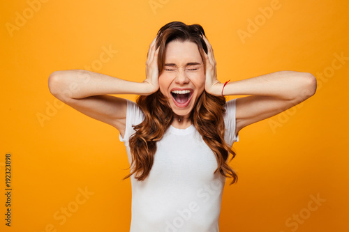 Screaming brunette woman in t-shirt covering her ears