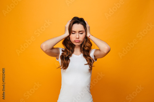 Confused brunette woman in t-shirt holding her head