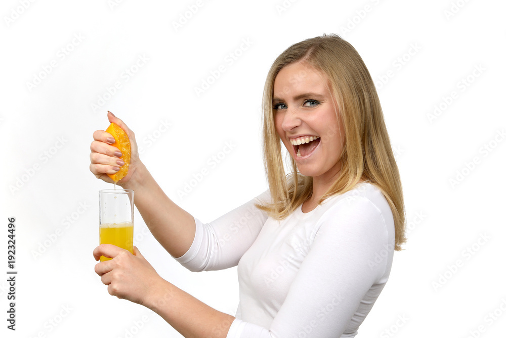 Hübsche blonde Frau begeistert presst eine Orange mit der Hand aus Saft läuft in ein Glas Hübsche blonde Frau begeistert presst eine Orange mit der Hand aus Saft läuft in ein Glas