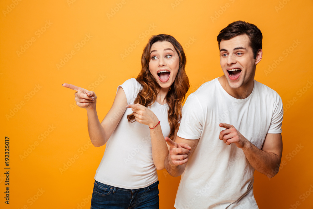 Happy screaming young lovely couple pointing and looking away