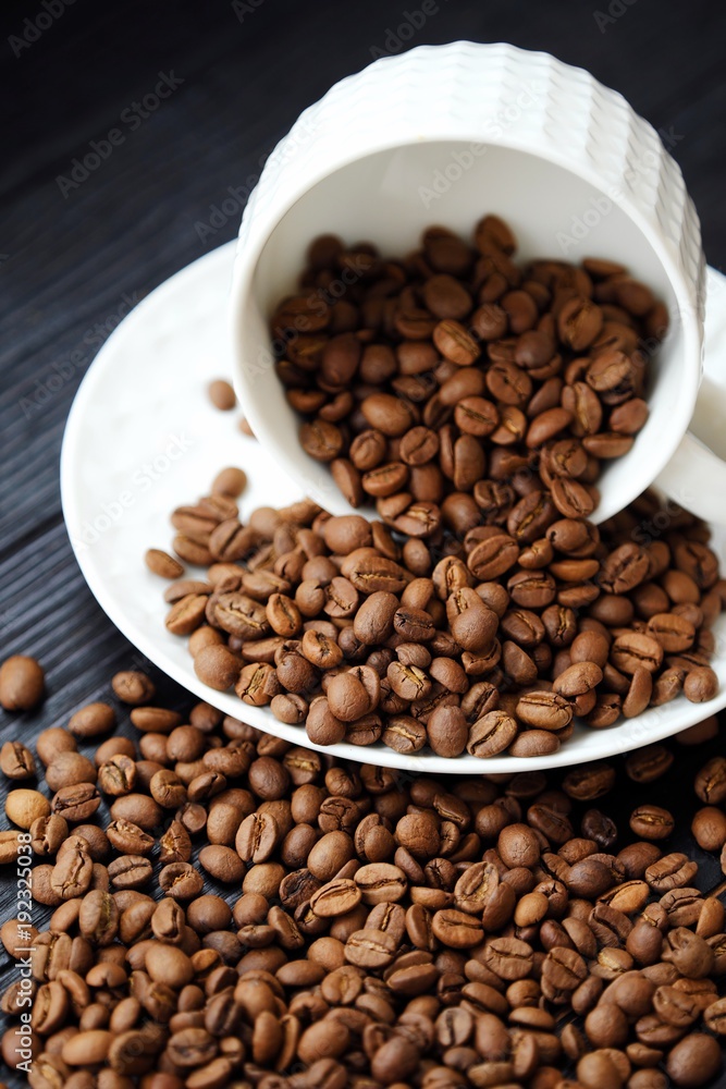 Roasted coffee beans in white mug on table Roasted coffee beans in white mug on table