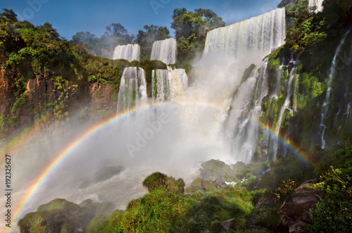 Full rainbow at amazing Iguazu falls  summer landscape with scenic waterfalls