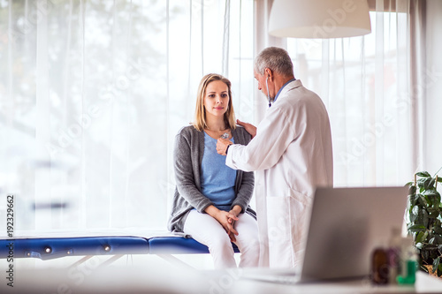 Senior doctor examining a young woman in office.