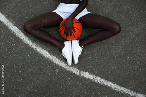 Slim sporty afro-american girl and orange basketball at stadium