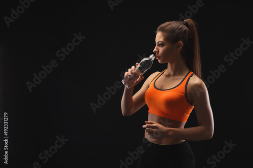 Female bodybuilder drinking water after workout