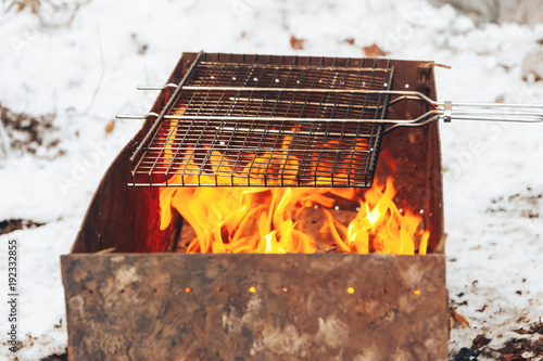 Flaming fire over hot coals in a portable summer barbecue photo
