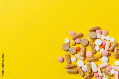 Medication white colorful round tablets arranged abstract on yellow color background. Aspirin, capsule pills for design. Health, treatment, choice healthy lifestyle concept. Copy space advertisement.