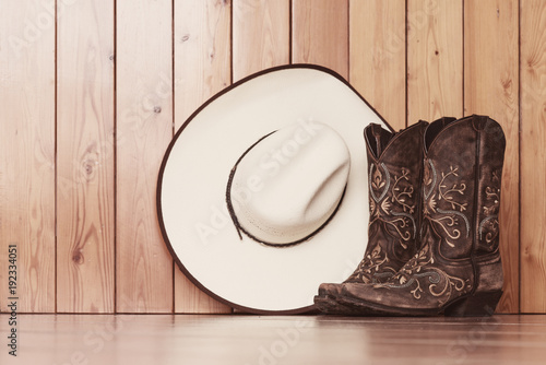 cowgirl embroidered boots and white hat on wooden background - text space