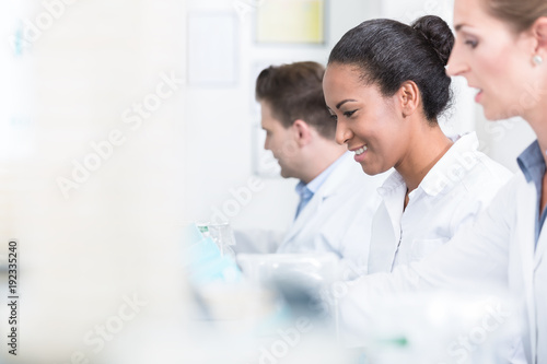 Group of researchers smiling during work on devices in laboratory