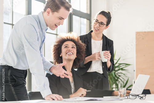 Canvas Print Young female employee asking for advice her helpful experienced colleagues in th