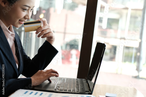 woman holding a credit card and using computer for online shopping at cafe. businesswoman purchase goods from internet at office. female startup make payment on bank website at workplace